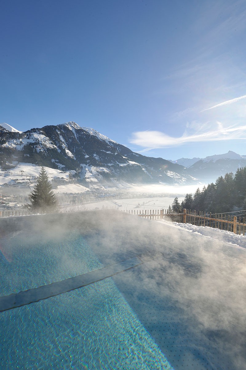 View over the steaming infinity pool to the snowy mountains