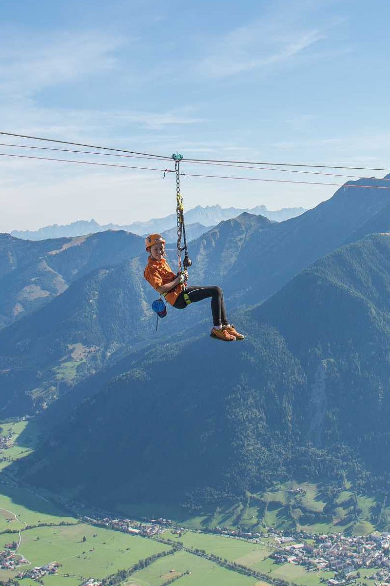 A woman hangs on a zipline over the mountains