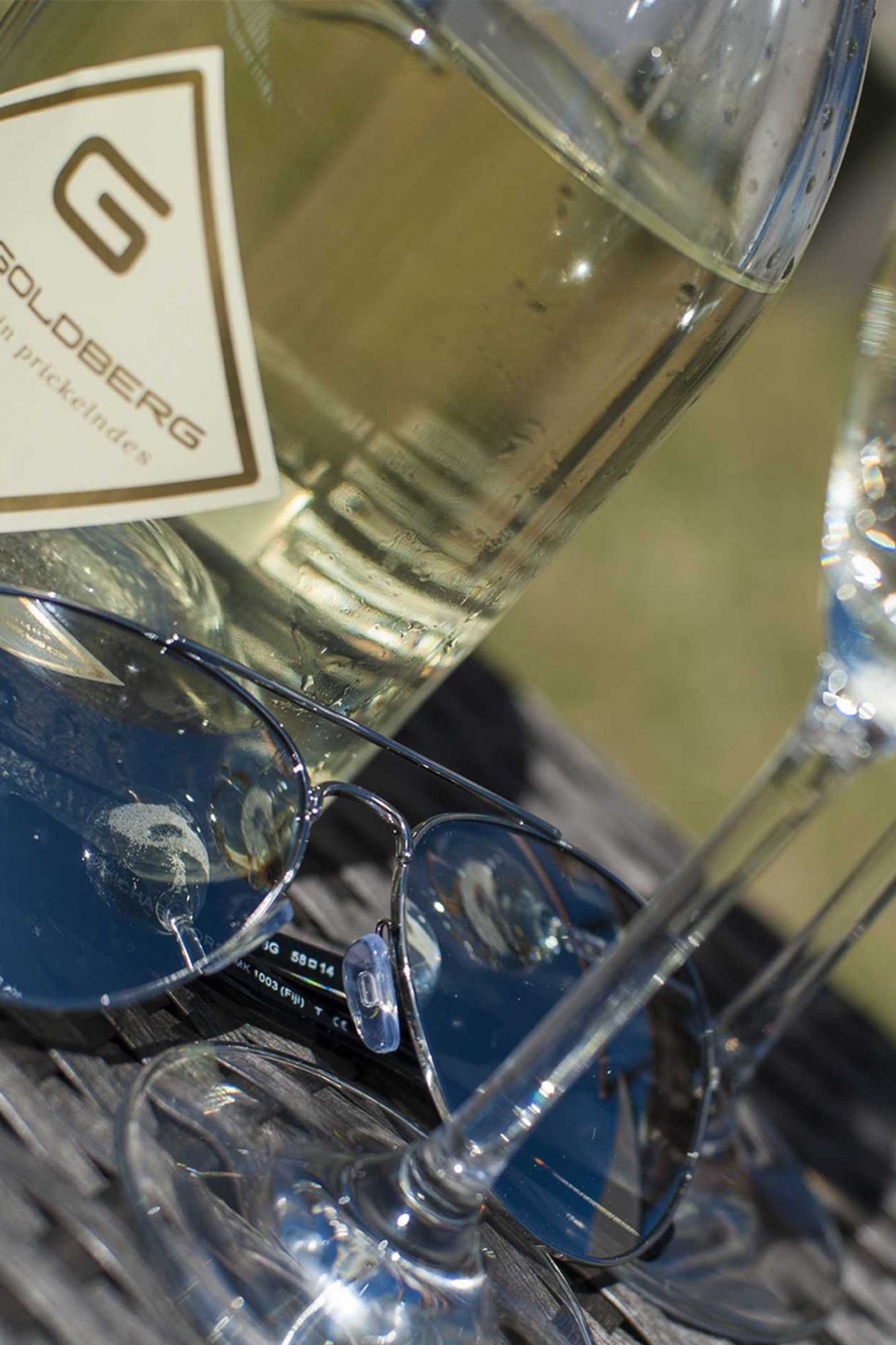 Detail of sunglasses lying between wine glasses