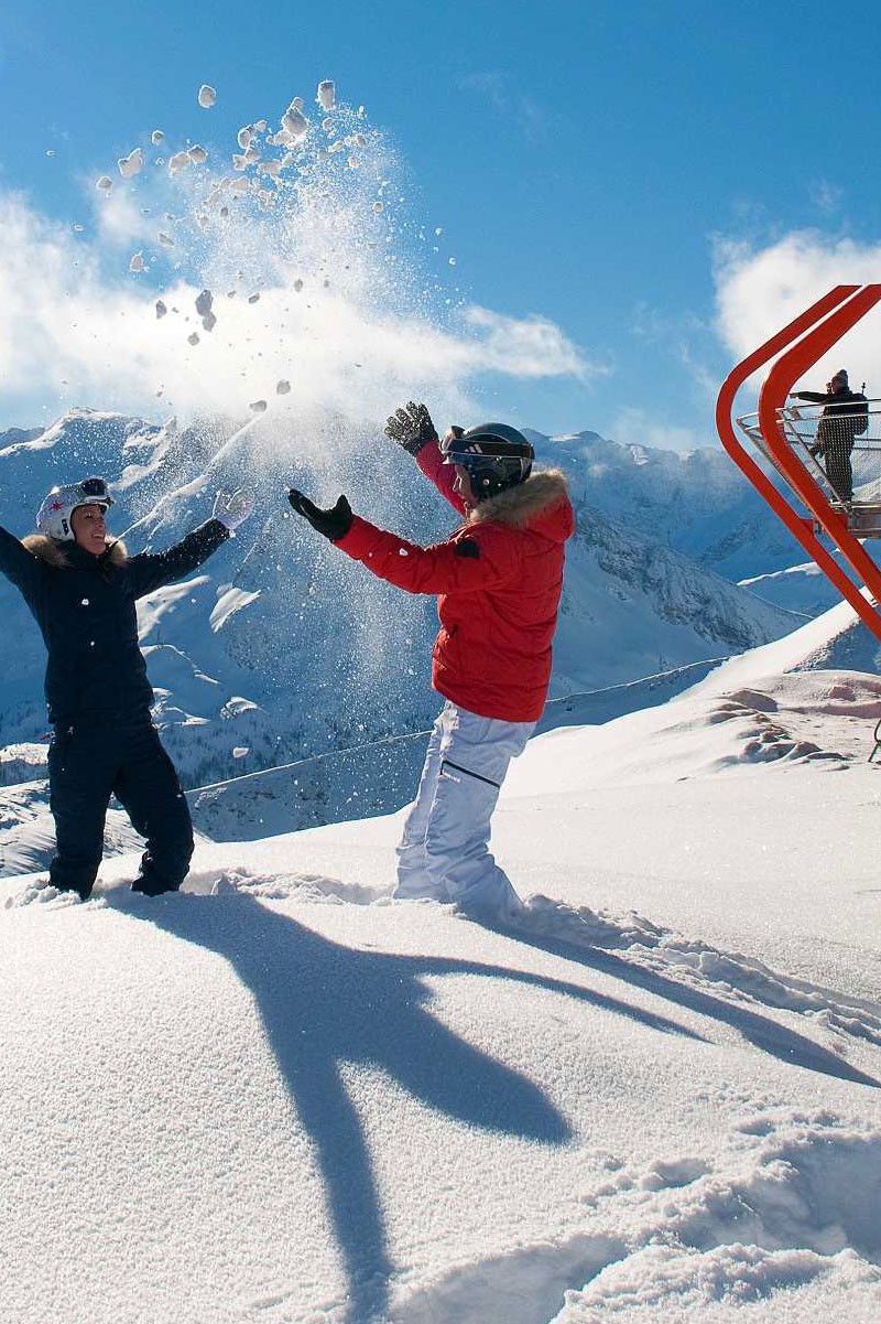 Zwei Menschen werfen Schnee im Skiurlaub direkt an der Piste
