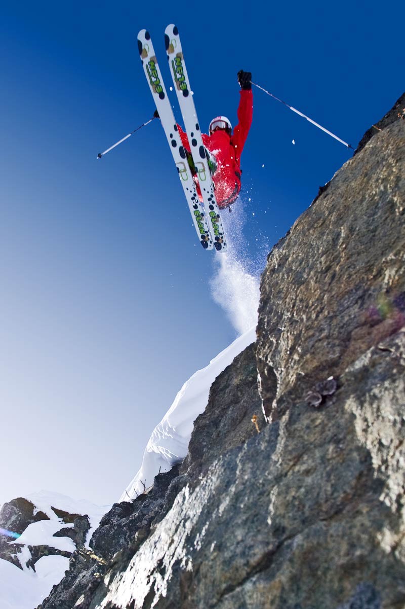 A person jumps with skis over a rocky ledge
